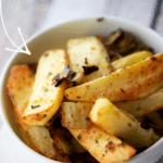 a white bowl on a wooden background with potato wedges