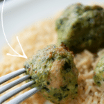 a close up of a spinach turkey meatball ona fork over brown rice