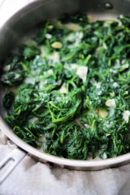 cooked spinach with garlic and parmesan cheese in a skillet