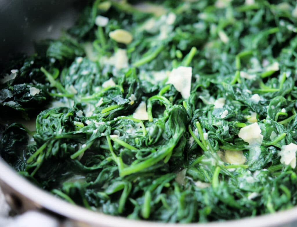 a close up of spinach with garlic and parmesan