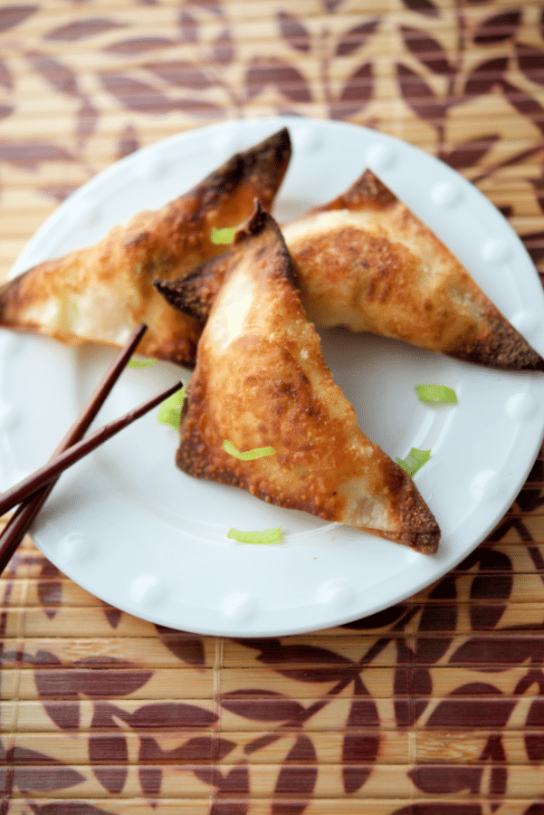 cooked crab rangoons on a plate with chopsticks