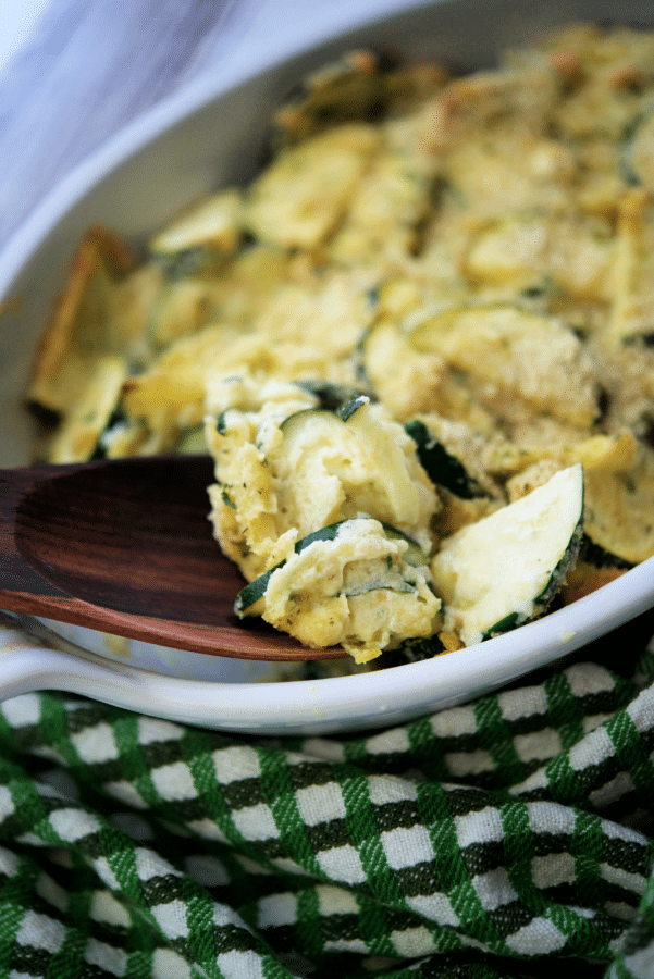 sliced zucchini topped with breadcrumbs in a white dish