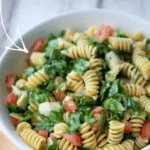 rotini pasta with spinach and artichokes in a white bowl