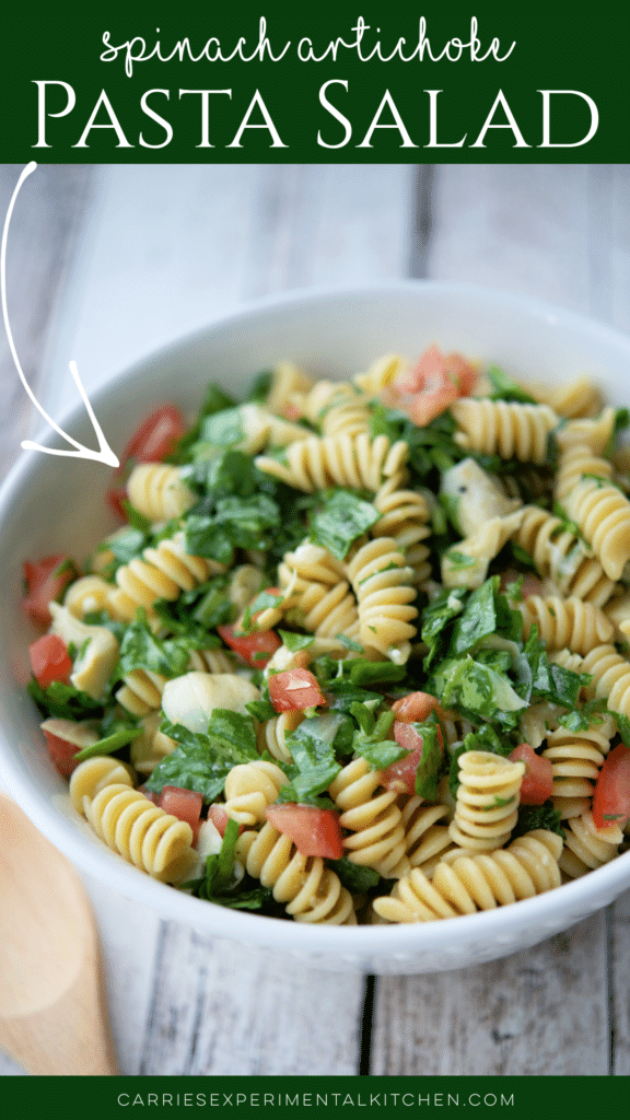 rotini pasta with spinach and artichokes in a white bowl