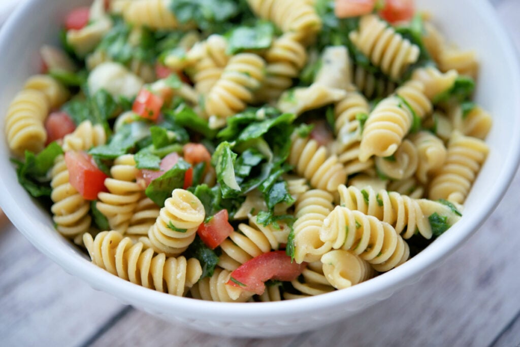 a close up of spinach artichoke pasta salad