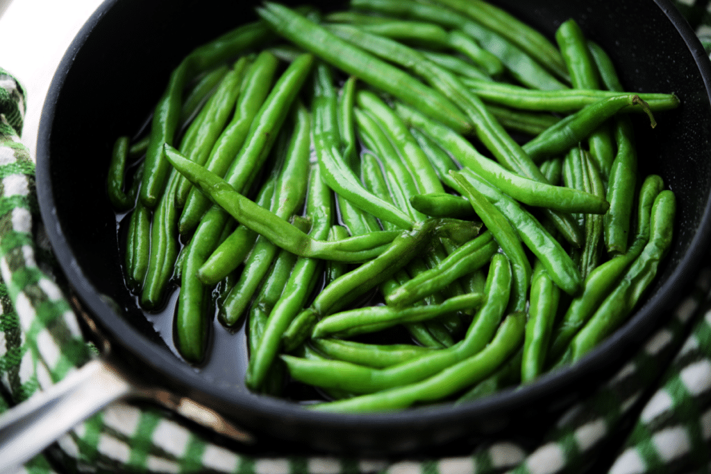 a close up of cooked green beans in a pan
