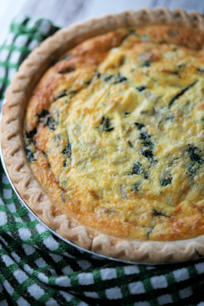 a pie plate with spinach artichoke quiche
