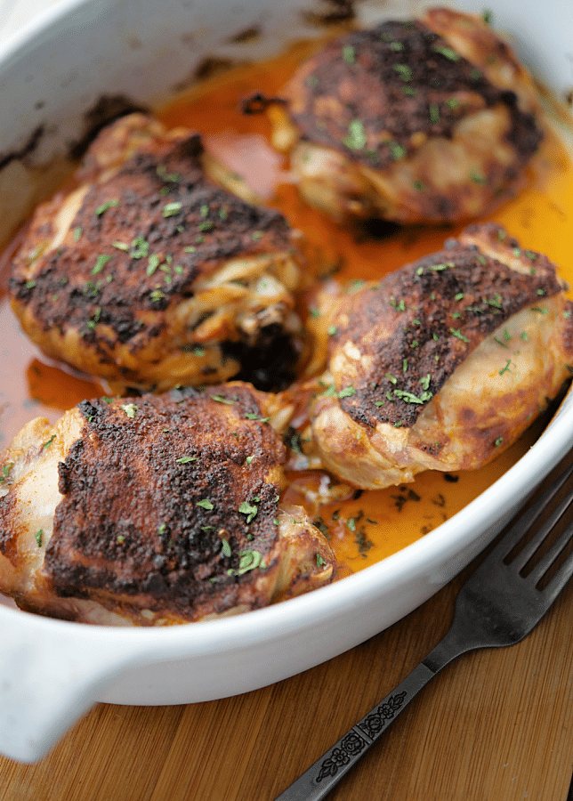 four paprika roasted chicken thighs in a white baking dish