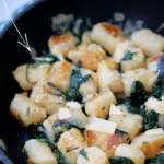 a skillet with cooked cauliflower gnocchi with spinach
