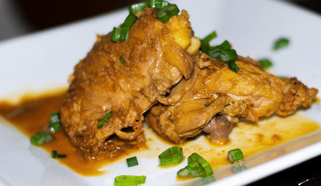 a close up of two pieces of soy sauce and lemon chicken on a plate