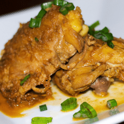 a close up of two pieces of soy sauce and lemon chicken on a plate