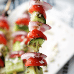a wooden skewer threaded with cucumbers, tomatoes, onions and olives