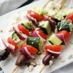 greek style appetizer skewers on a white platter