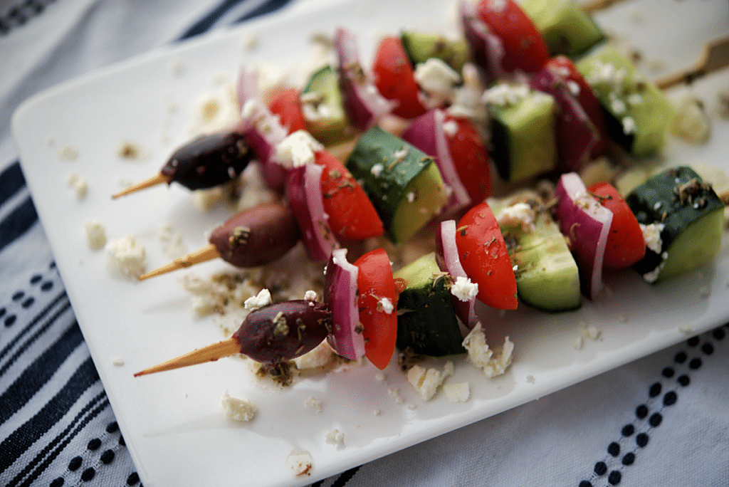 a close up of four skewers with vegetables on a plate