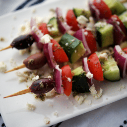 a close up of four skewers with vegetables on a plate