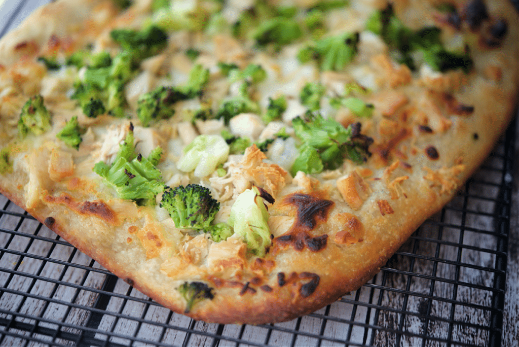 a close up of chicken broccoli flatbread