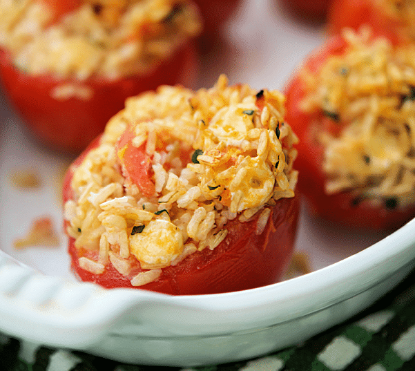 a white dish with cooked rice stuffed tomatoes