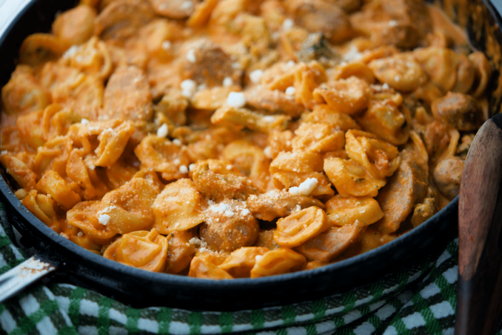 a close up of tortellini with sausage and brococli