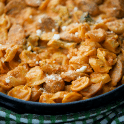 a close up of tortellini with sausage and brococli