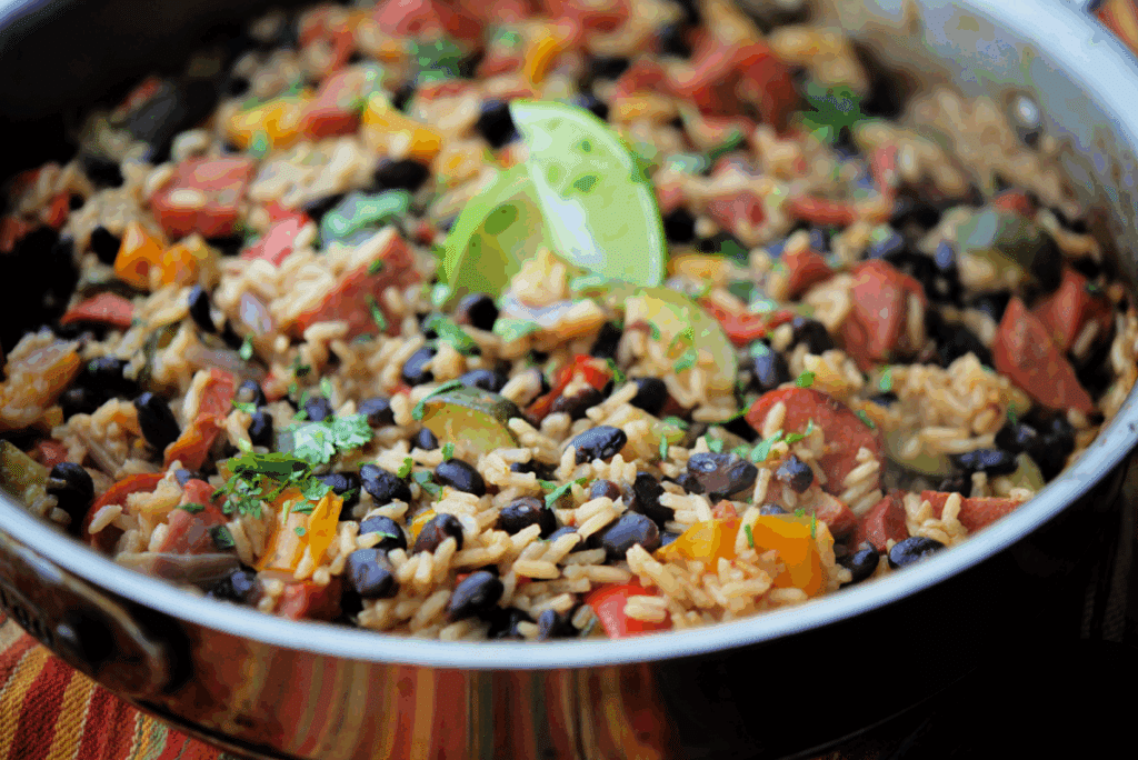 a close up of a skillet with chourico, rice and beans