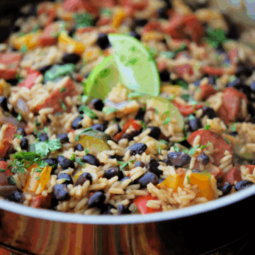 a close up of a skillet with chourico, rice and beans
