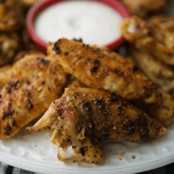 a close up of a plate of lemon pepper chicken wings
